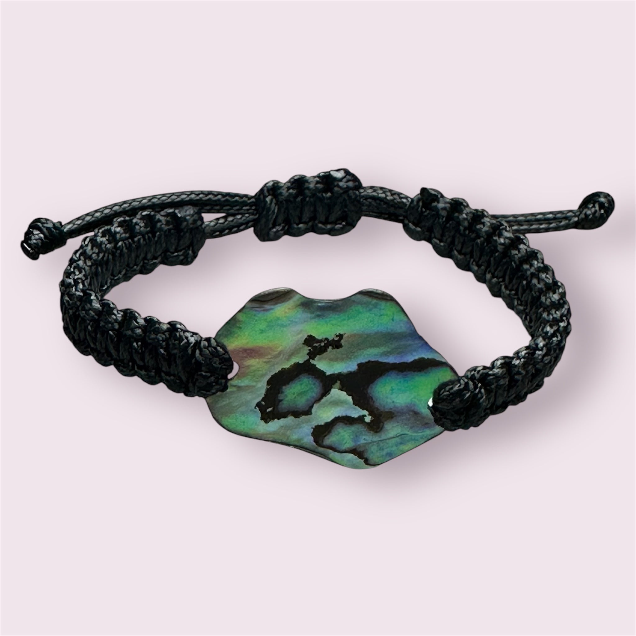 Close-up of adjustable black cord bracelet featuring an iridescent Paua shell from NZ.