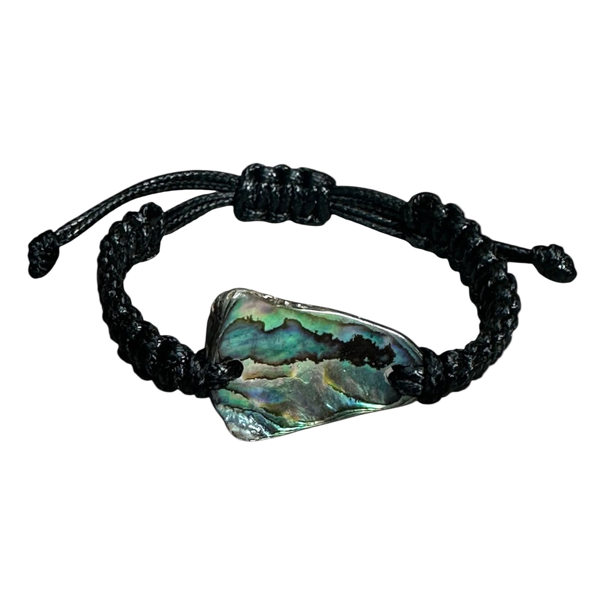 Black knotted bracelet with shimmering shell, styled next to shells and beach elements.